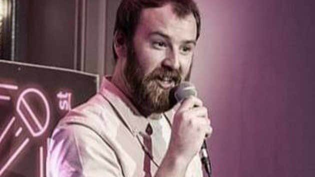 A man with a beard holding a mic, talking