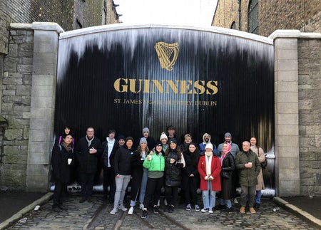 A large tour group standing in front of the Guinness Storehouse gates
