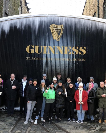 A large tour group standing in front of the Guinness Storehouse gates