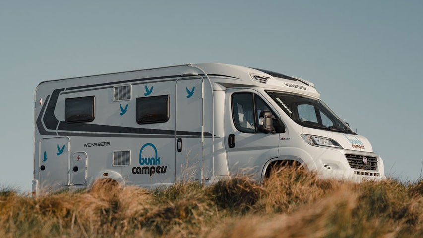 A Bunk Campervan parked beside thick yellow grass