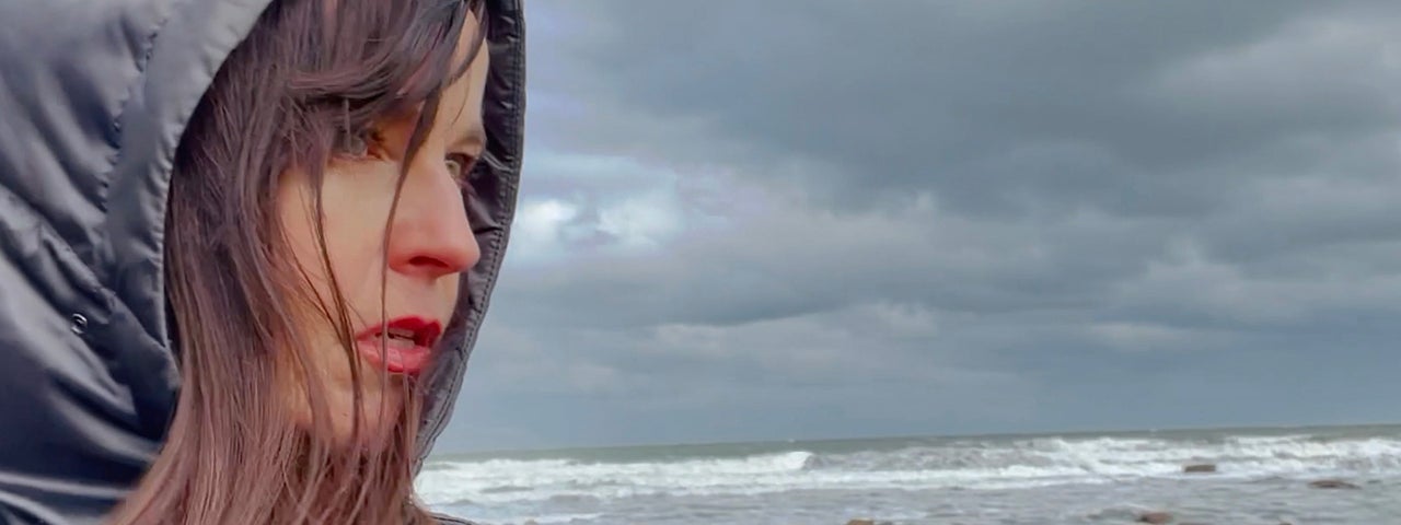 A woman stands in front of a grey sky