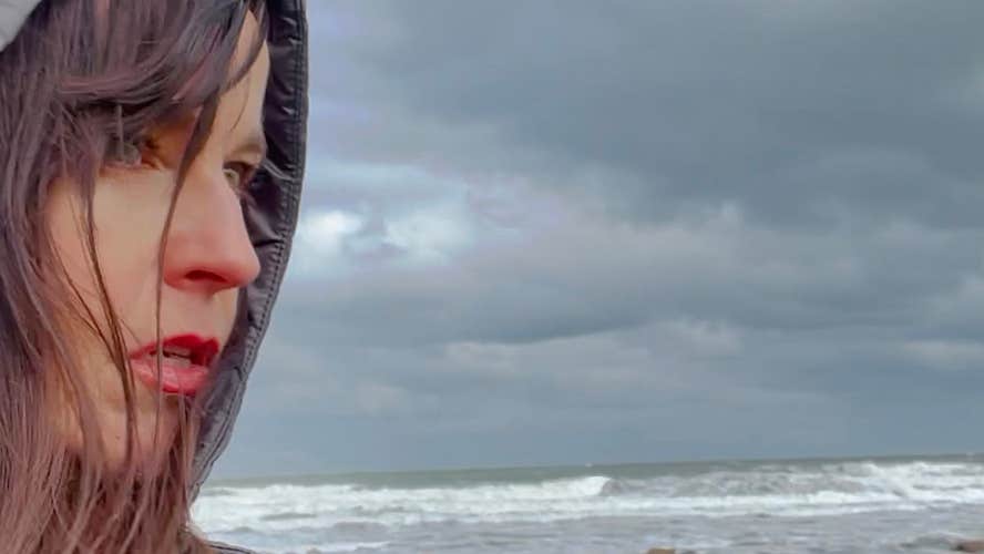 A woman stands in front of a grey sky