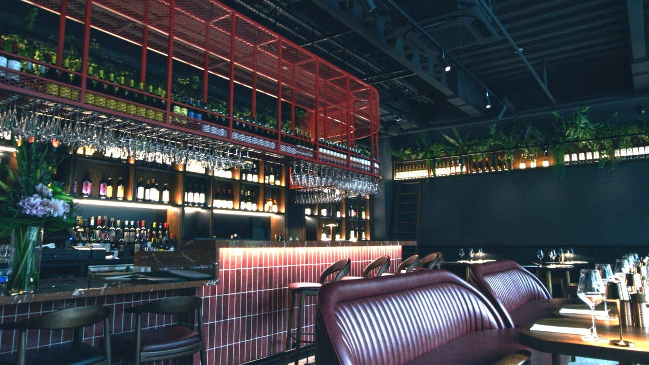 Modern bar area and dark coloured interior of a restaurant with leather seating at tables