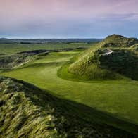 Golf course and bunker with a blue and pink sky in the background