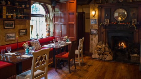 A view of the dining room with a fire in the fire place at Wright's Anglers Rest