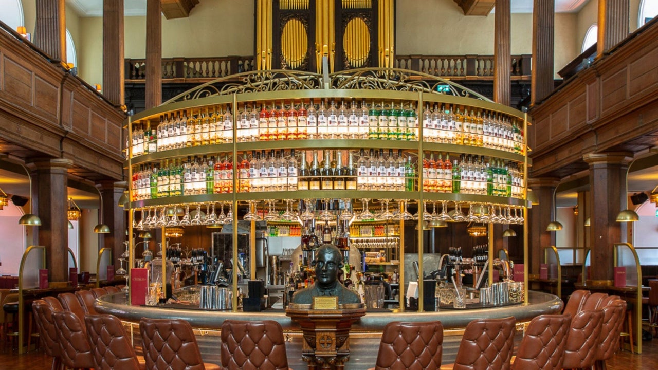 A circular bar with chairs around it and a display of bottles behind the bar