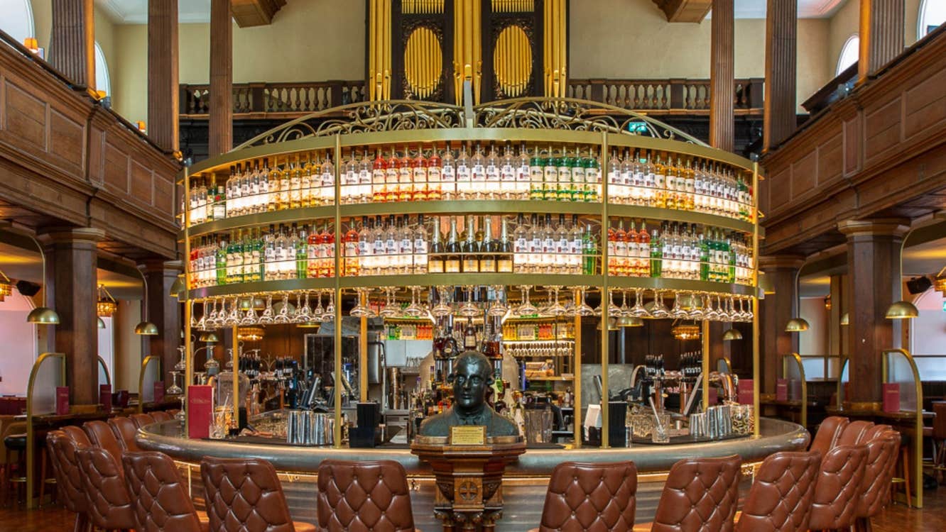 A circular bar with chairs around it and a display of bottles behind the bar