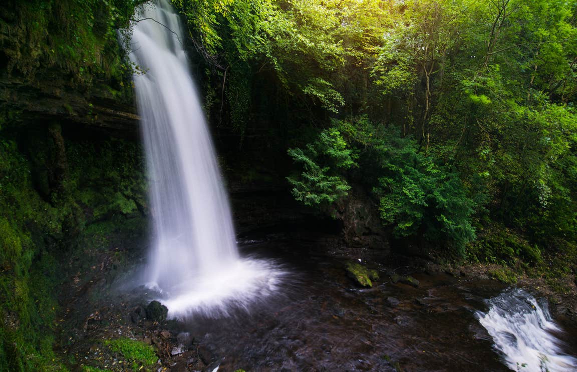A waterfall cascading past rich greenery
