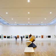 A gallery with artworks on the walls and a sculpture in the centre of the room