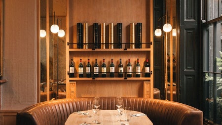 Table and chairs set in front of a domed shelving unit displaying wine