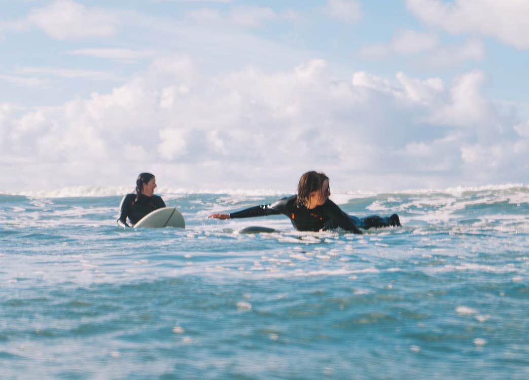 Two surfers lying on their surf boards at sea waiting for a wave