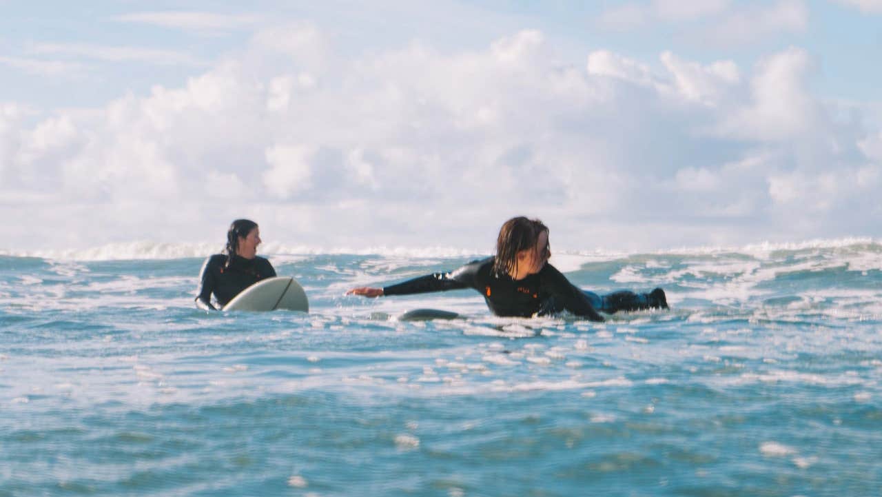 Two surfers lying on their surf boards at sea waiting for a wave