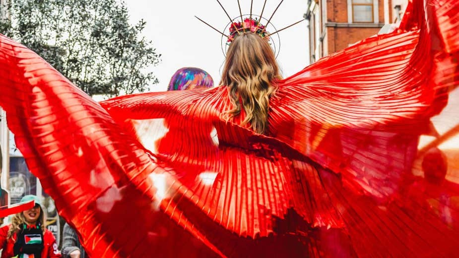 Brigit 2026: Dublin City Celebrating Women - rear view of woman in parade in wide red outfit.