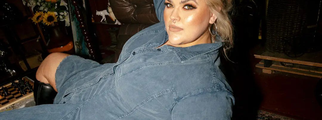 A woman in a blue denim dress is laying draped across a chair