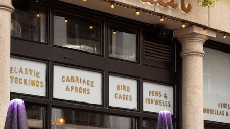 Outside a pub with a neon sign on the window and two unopened umbrellas