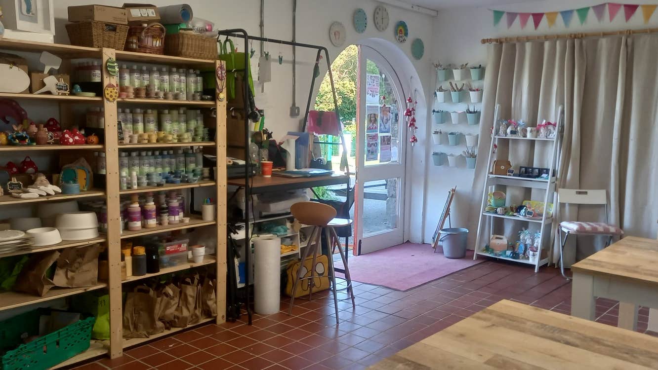 The interior of a decorated pottery studio with shelves of ceramics and benches
