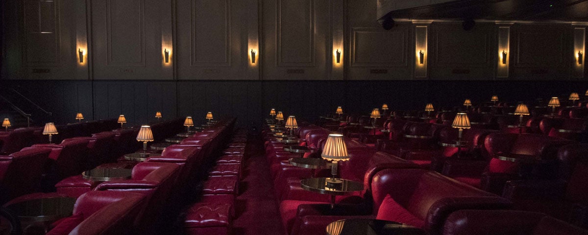 A view of seats in a cinema with old fashioned side tables and lamps