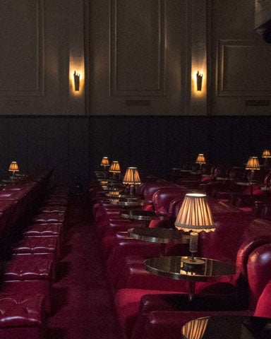 A view of seats in a cinema with old fashioned side tables and lamps