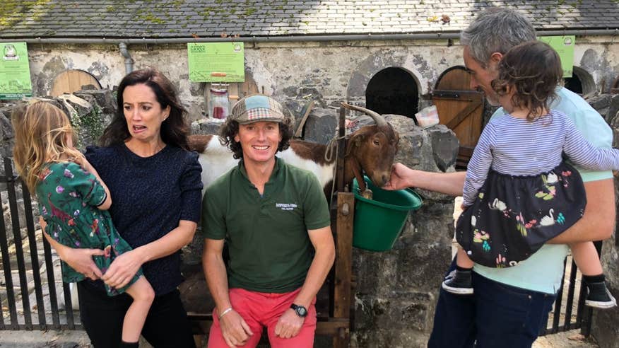 A family visiting Maperath Farm in County Meath, Ireland, and petting a goat.