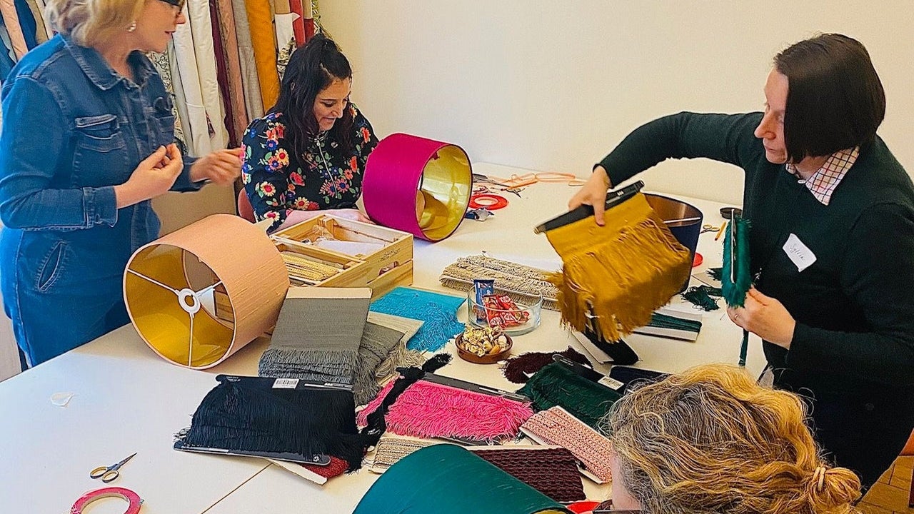 A group working at a table covered with fabrics and frames as they create lampshades during a workshop