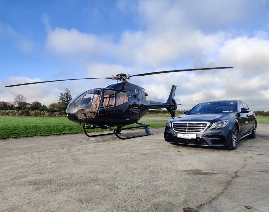 A luxury car parked beside a helicopter