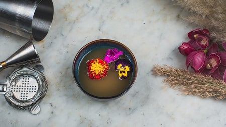 A soup bowl decorated with three flower heads in the soup