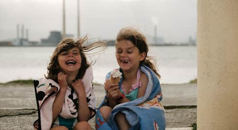 Two girls laughing and eating ice cream cones