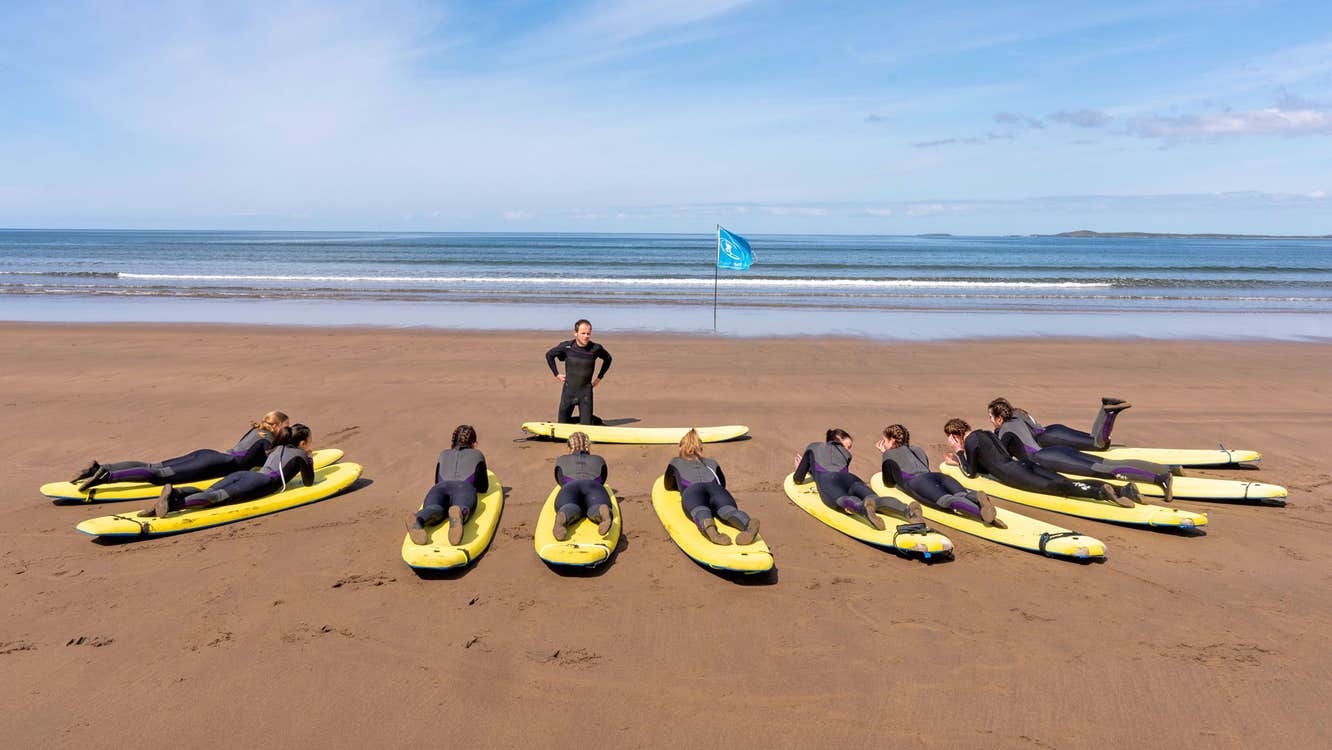 Strandhill Surf School view of ten surfers on boards on the beach with the instructor