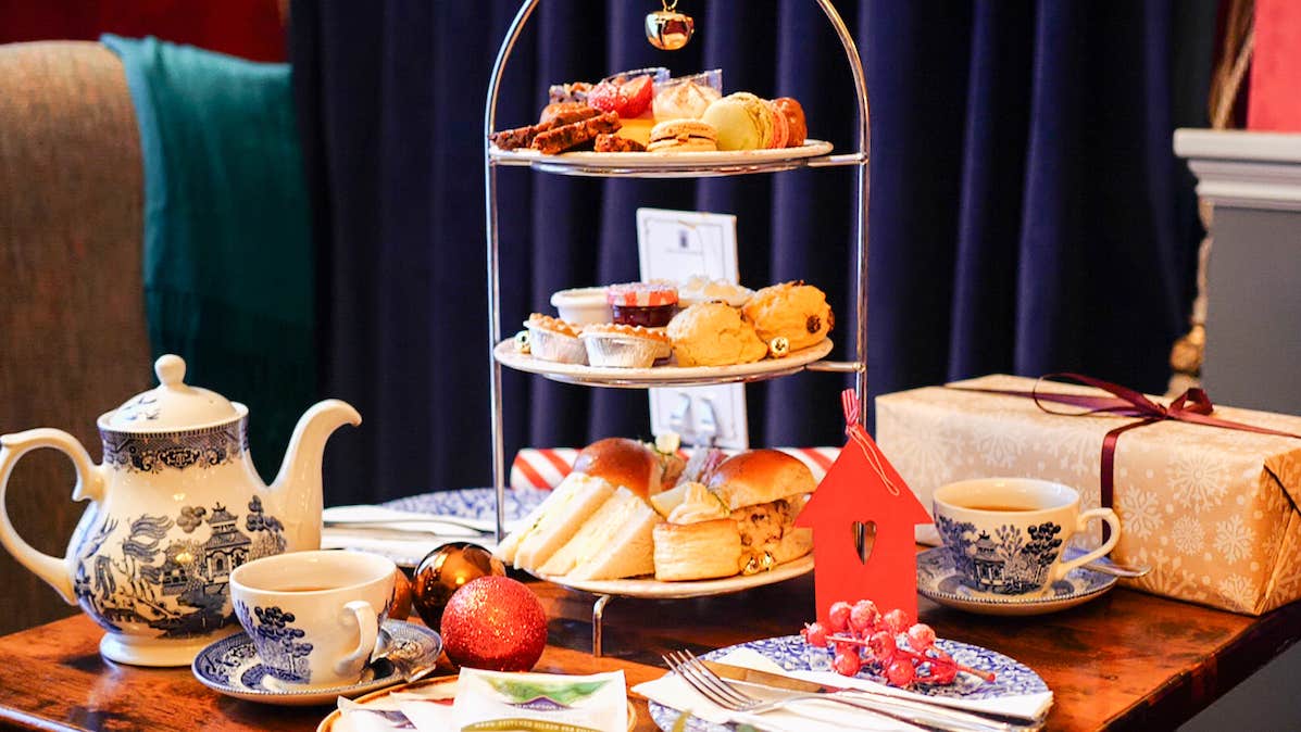 Festive Afternoon Tea stand at Old Music Shop restaurant, the Castle Hotel. Sandwiches, pastries, scone, selection of teas, gifts, Christmas decorations place on a table.