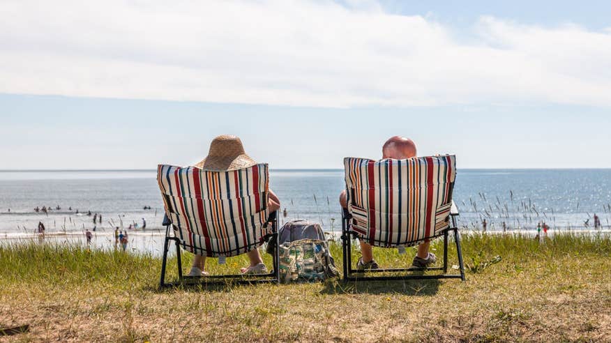 Two people relaxing on sunloungers at the beach