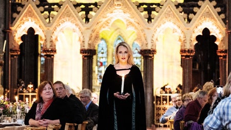 Person in medieval clothing standing between two tables in a banquet hall