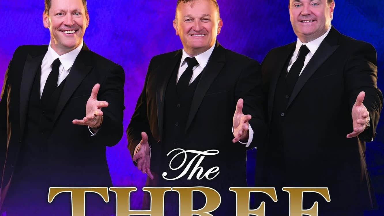 3 smiling men in dark suits and ties all with their left hands outstretched forwards.