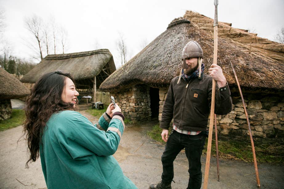 A woman taking a picture of a man posing in a Viking helmet at the Irish National Heritage Centre in County Wexford.