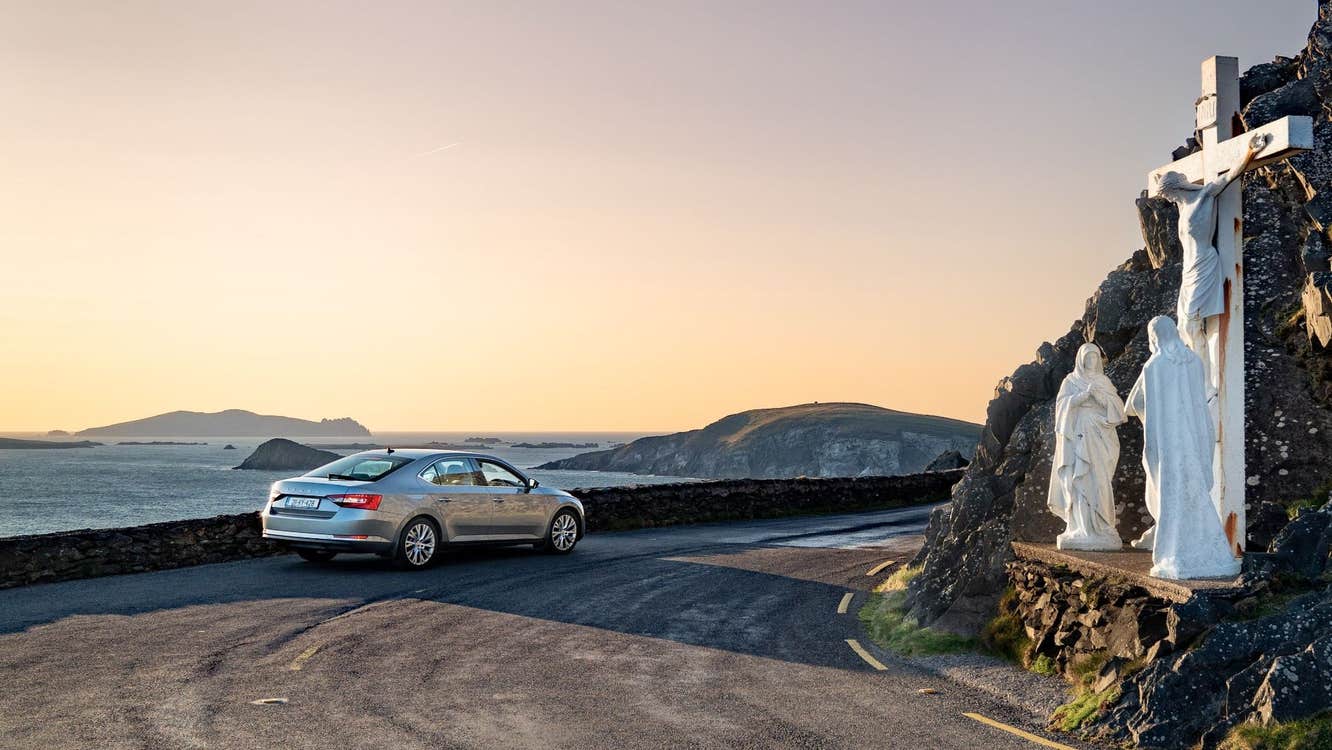 A car parked in front of a grotto depicting the Crucifixion