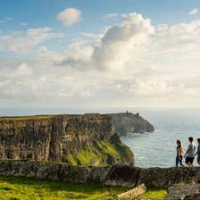 Three people walking along a cliff top