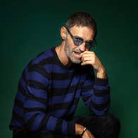 A man in sunglasses with one hand up to his mouth