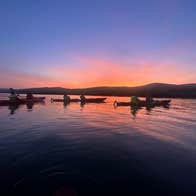 A group of kayakers on Kenmare Bay with a colourful sunset
