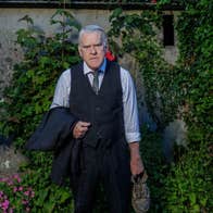 The Man In The Woman’s Shoes at Backstage - a grumpy looking man in shirt and tie holding a jacket in one hand and an old shoe in the other.
