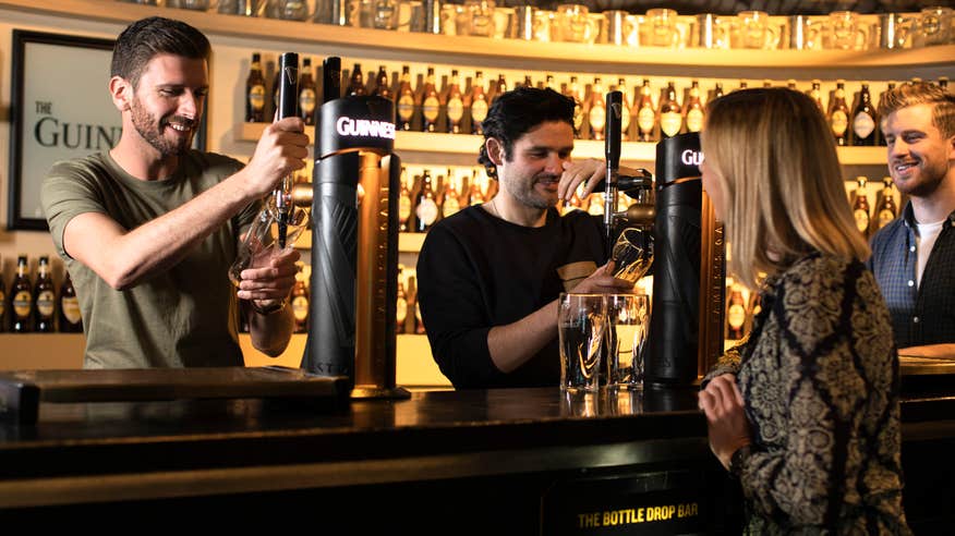 People pulling a pint at the Guinness Storehouse in Dublin city