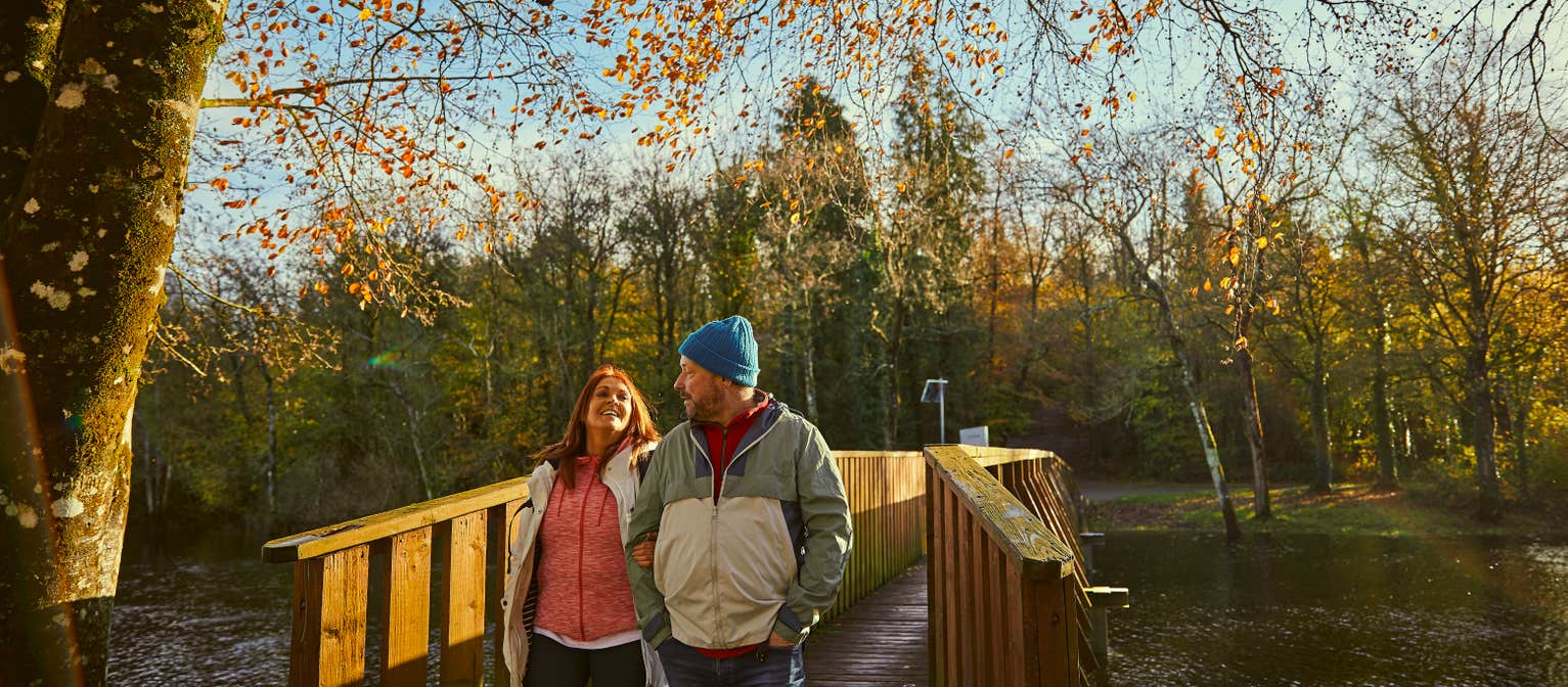 Couple walking under autumn leaves in Killykeen Forest Park.