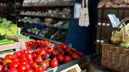 Tomatoes and leafy green vegetables on display in a farm shop