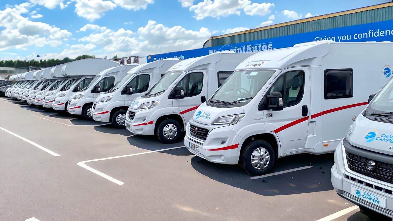 Row of campervans parked outside a rental agency building