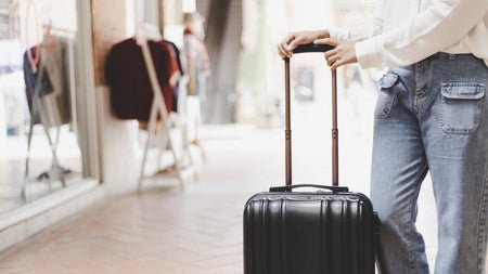 A person standing next to a black suitcase