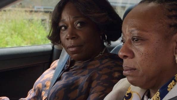 2 serious looking women are seated in a car.