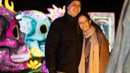 Two visitors posing among brightly lit skeleton lantern sculptures at Dublin Zoo Wild Lights