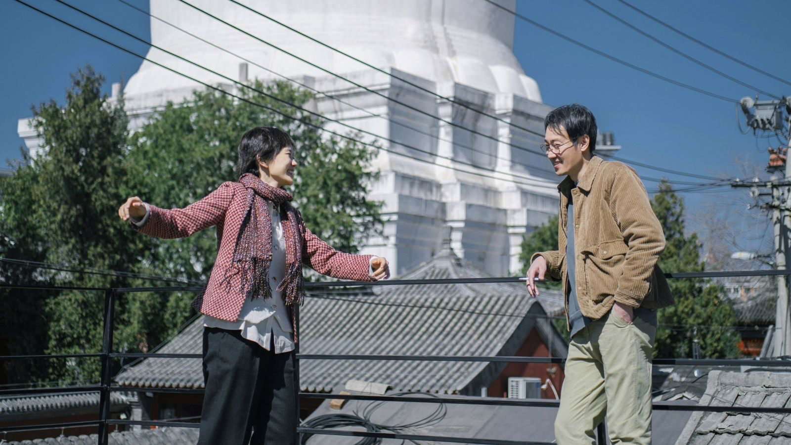 A man and a woman are talking to each other on a roof.