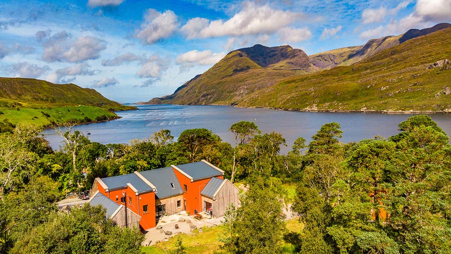 View of orange house with water and mountains in background