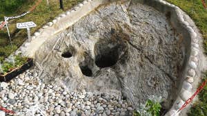 Image of a holy well surrounded by stones and grass.