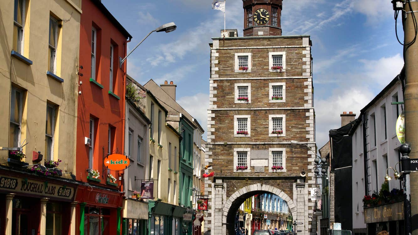 Youghal Clock Gate Tower, shop fronts and cars on a busy street