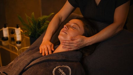 A guest enjoying a gentle facial massage in a softly lit treatment room.